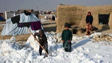 Afghan internally-displaced children shovel snow near their tents during a cold winter day at Nahr-e Shah-e- district of Balkh Province, near Mazar-i-Sharif on January 17, 2023. (Photo by Atif ARYAN / AFP)